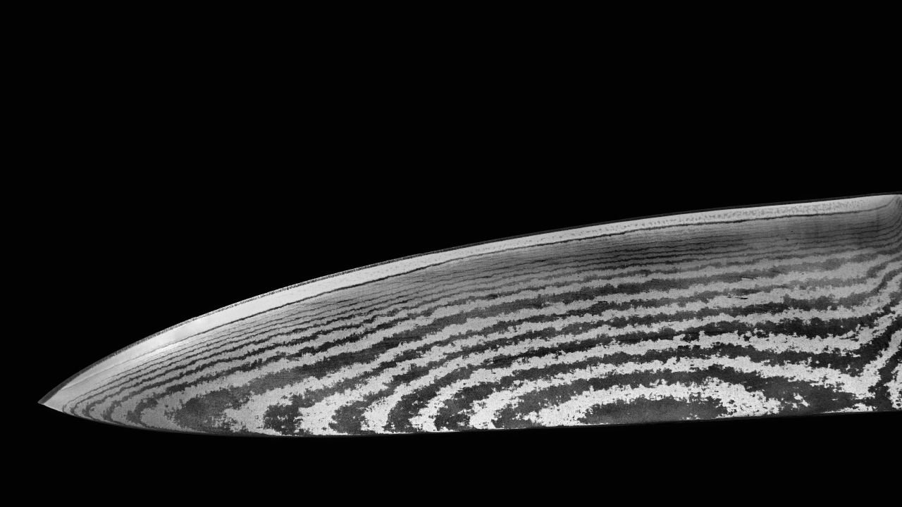 Close-up of a Damascus steel knife blade showing intricate layered patterns on a black background.
