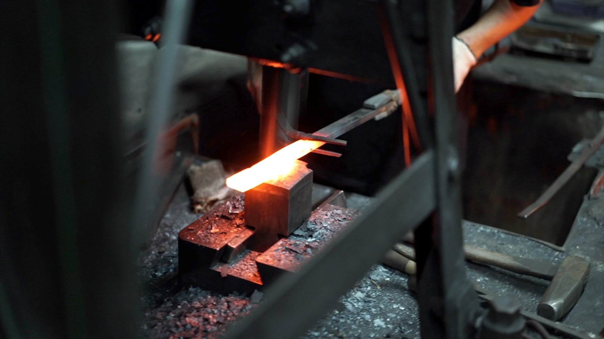 Sparks flying as a craftsman hammers red-hot steel in a traditional Japanese forge.