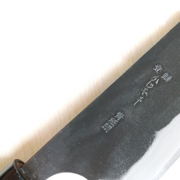 Close-up of a black blade with engraved text on a white background
