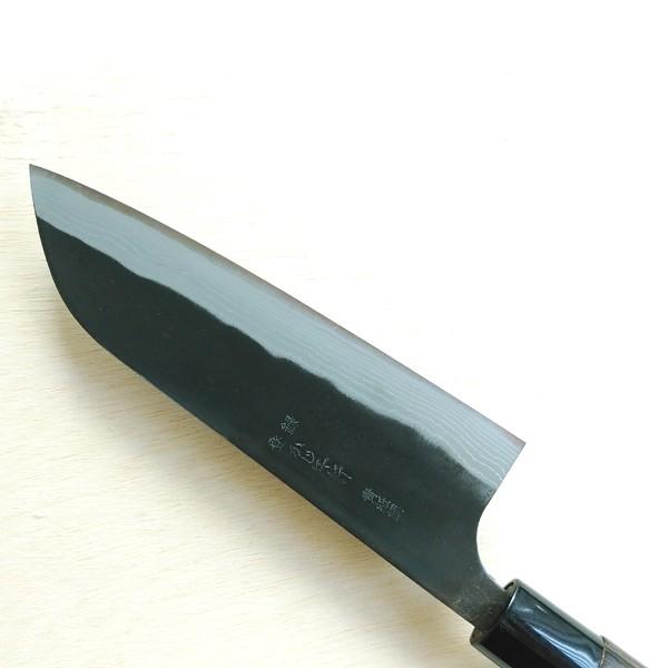 Close-up of a black-handled knife blade on a light wooden surface