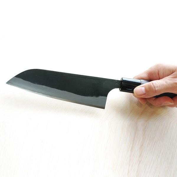 Hand holding a large knife on a white surface