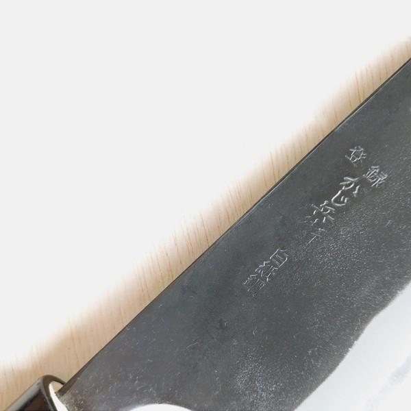 Close-up of a black knife blade with engraved text on a white background